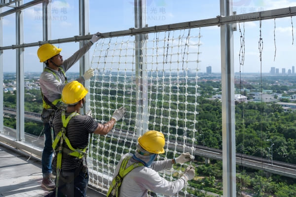 Installation team easily handling lightweight LED mesh panels on a building facade
